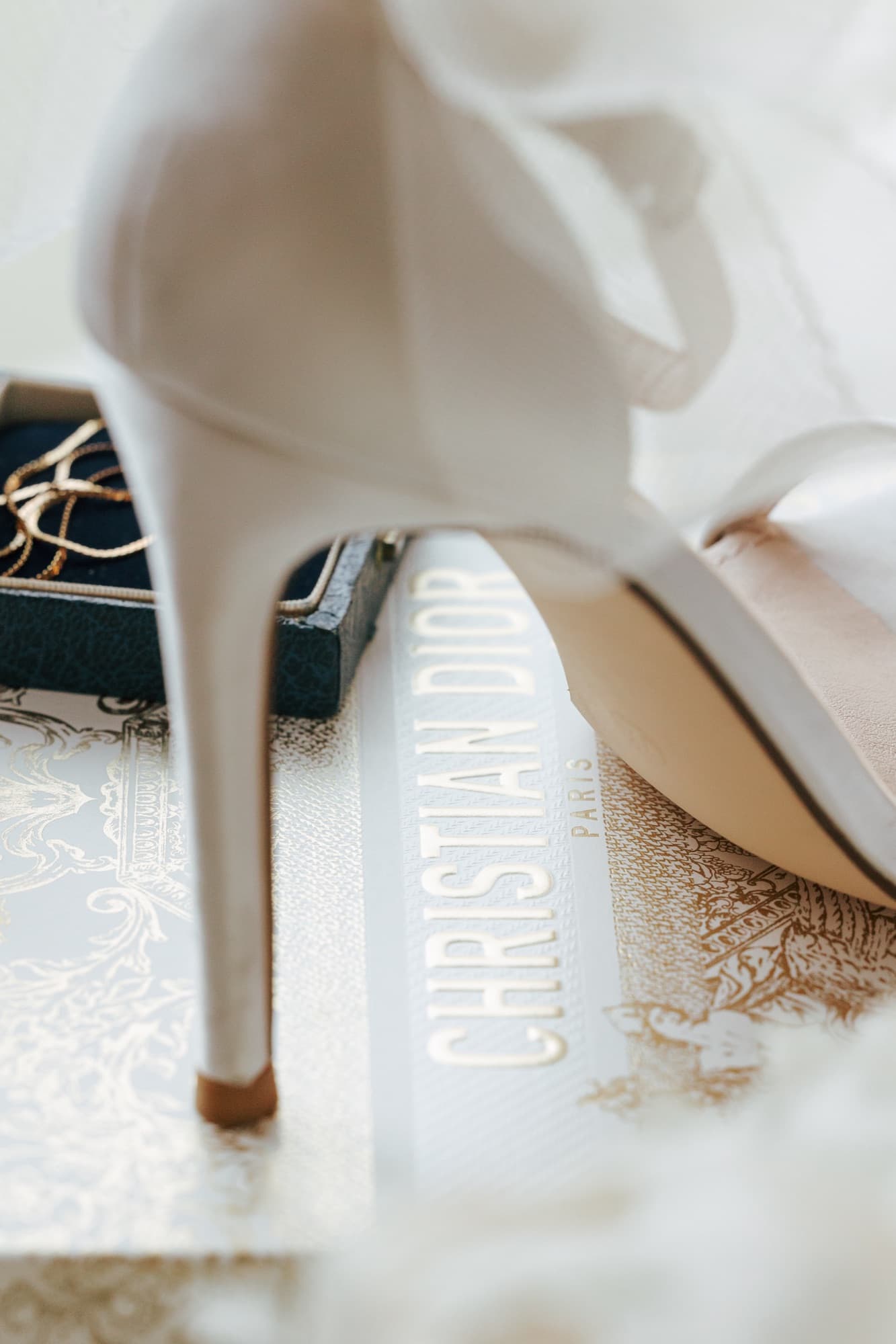 Bridal heel resting on a Christian Dior book, editorial wedding detail photography